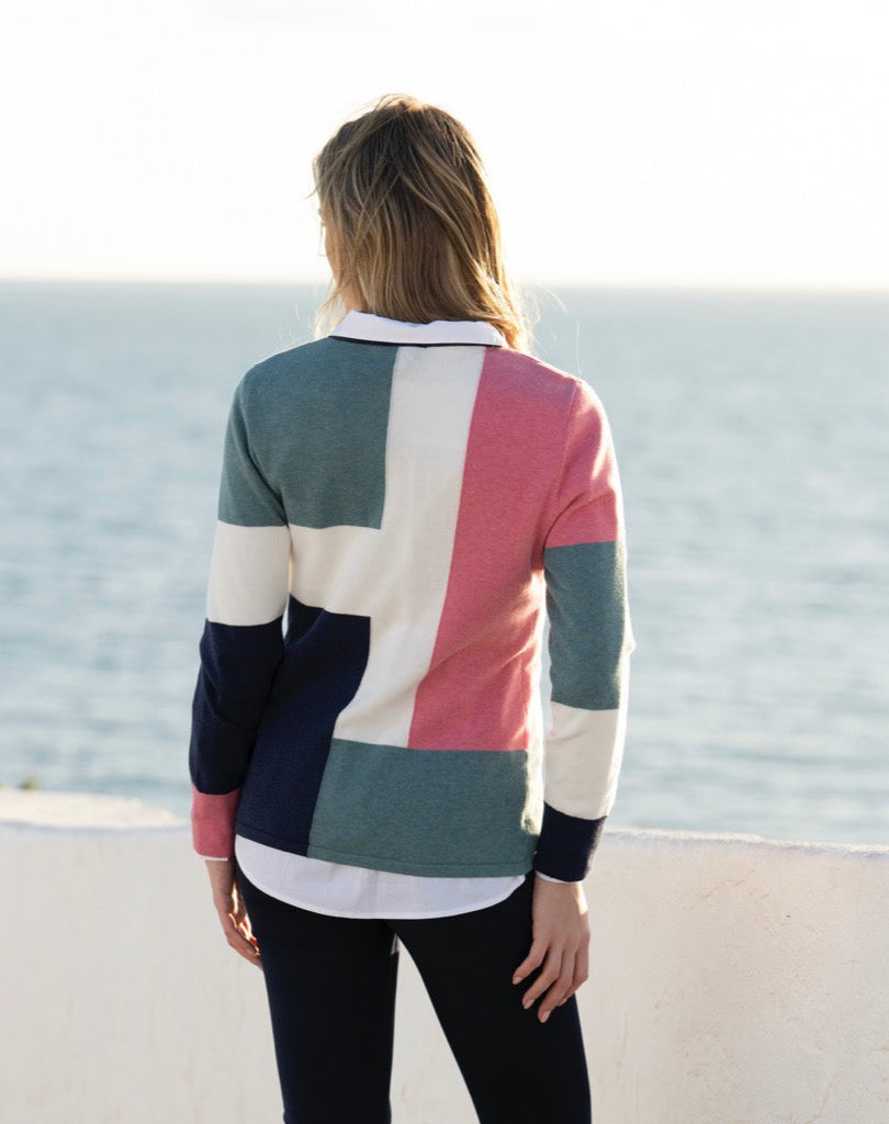 Person wearing a colorful sweater by the ocean