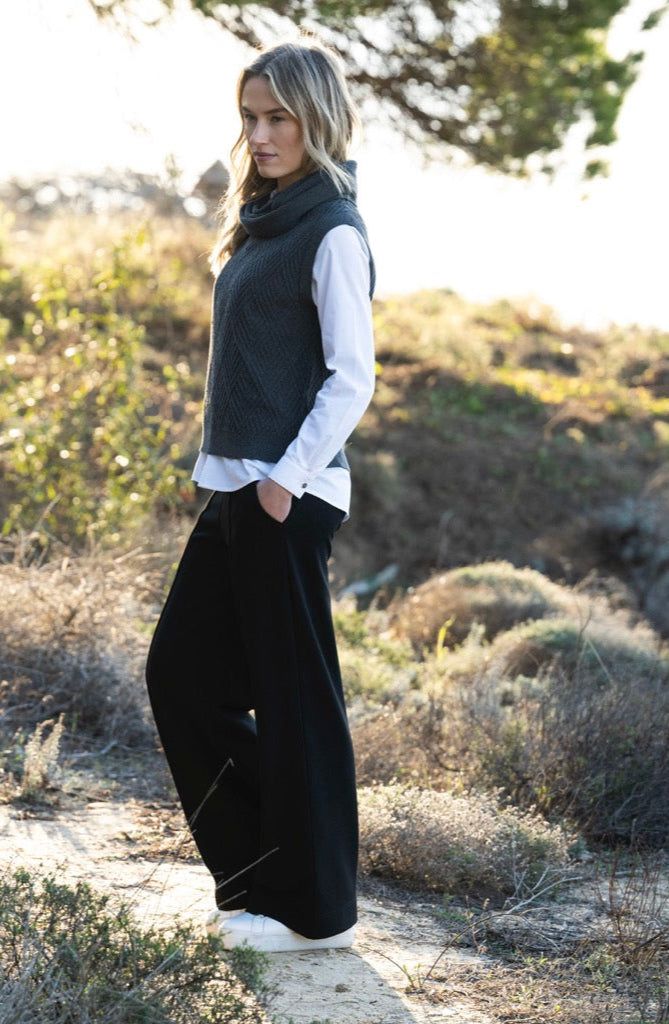 Woman standing in a natural landscape with greenery and sunlight.