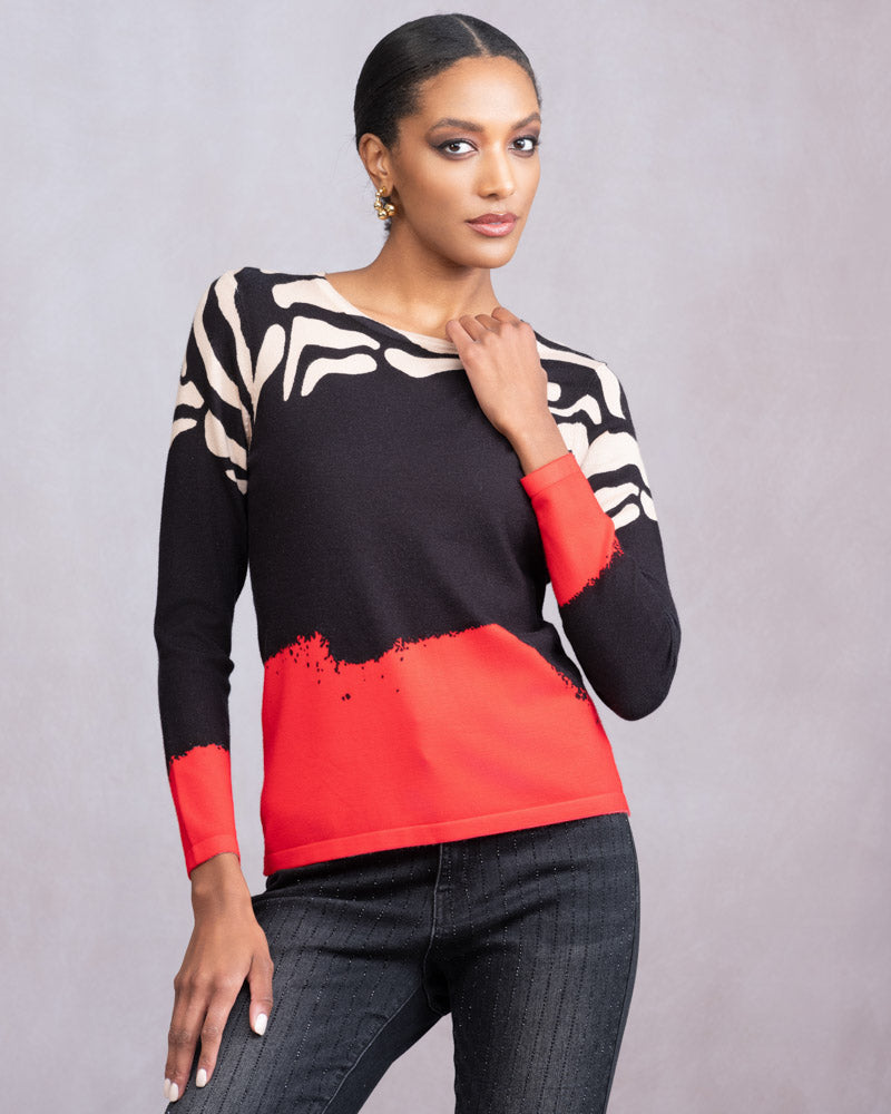 Woman wearing a black, white, and red patterned top against a gray background