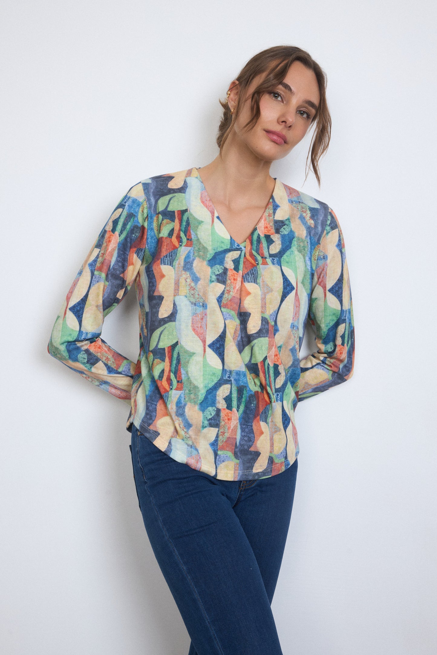 Woman wearing a colorful patterned blouse against a white background