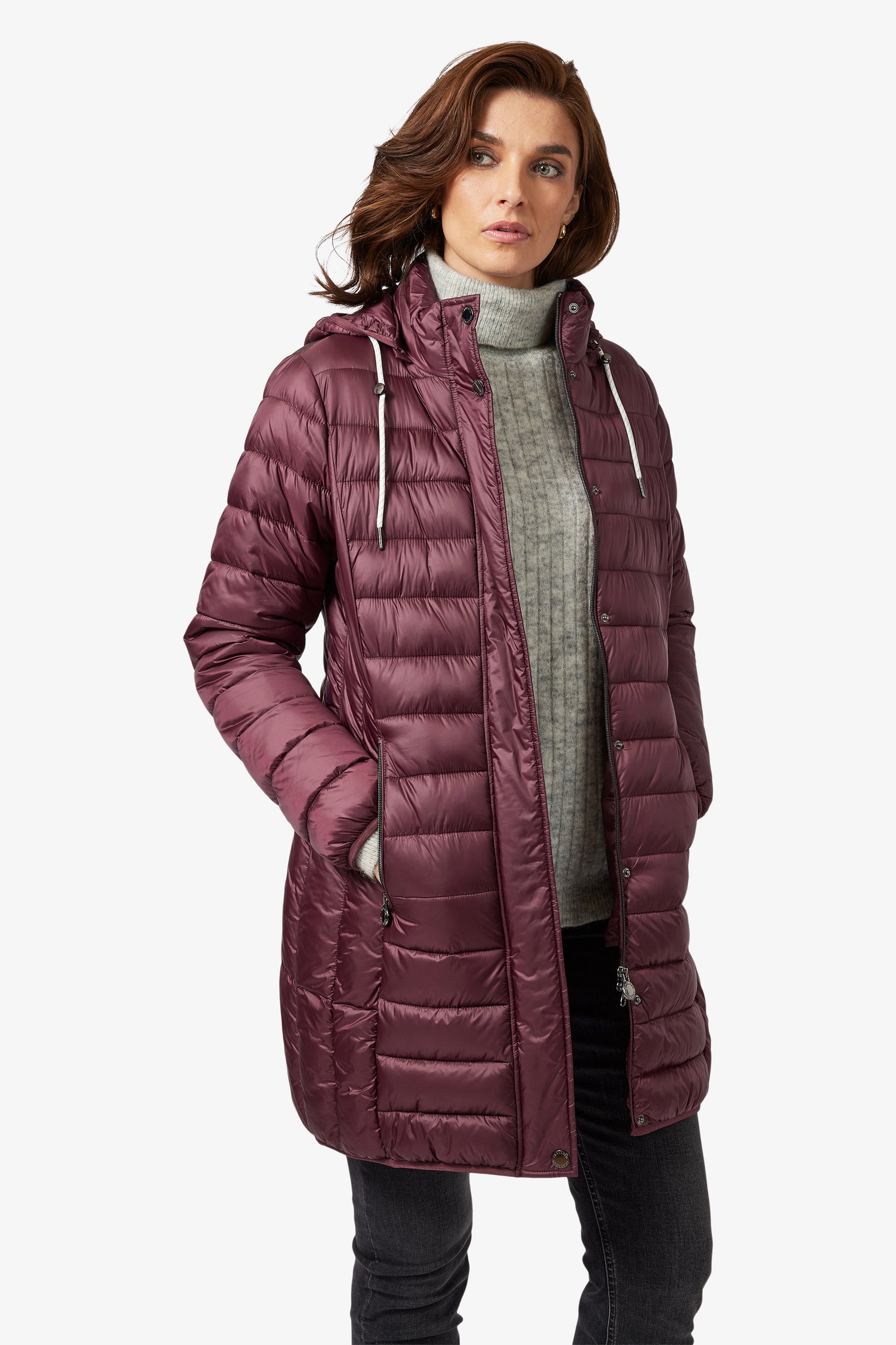 Woman wearing a long purple puffer coat on a white background