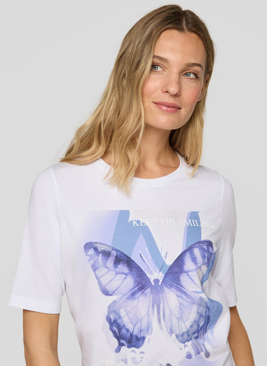 Woman wearing a white t-shirt with a blue butterfly design and Kering logo.