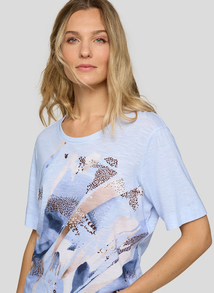 Woman wearing a light blue t-shirt with abstract animal print on a plain background