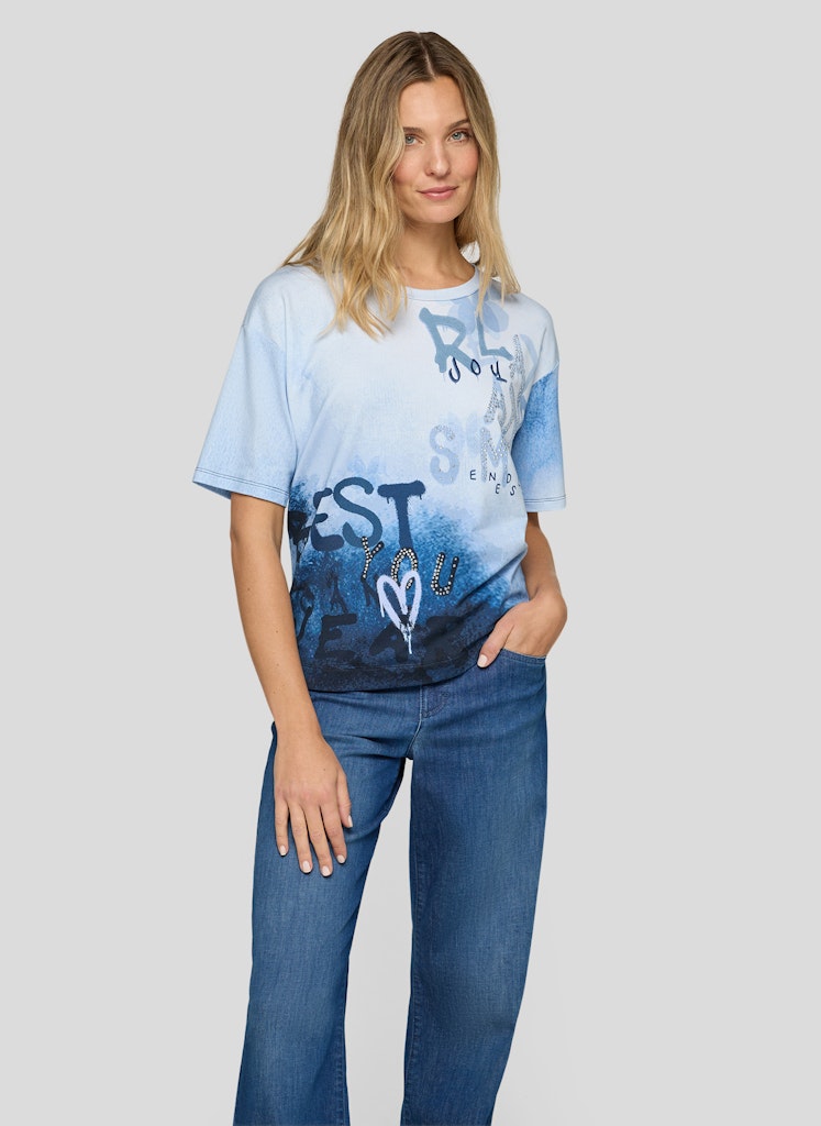 Woman wearing a blue and white gradient t-shirt with text and graphics on a plain background