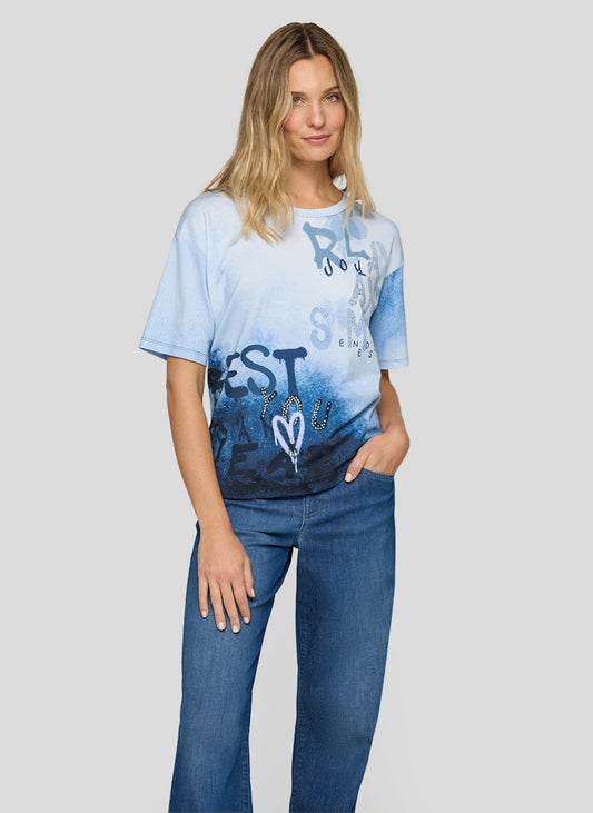 Woman wearing a blue and white gradient t-shirt with text and graphics on a plain background