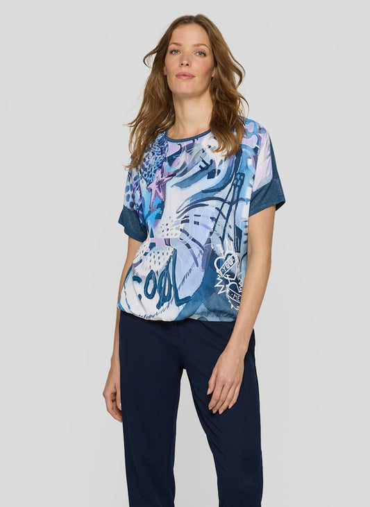 Woman wearing a colorful patterned top and navy pants on a white background