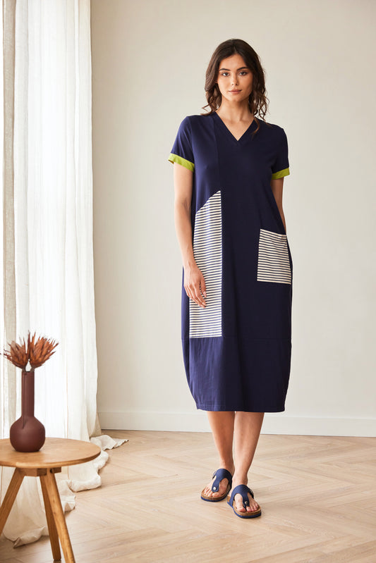 Woman wearing a navy dress with white geometric patterns in a minimalistic room.
