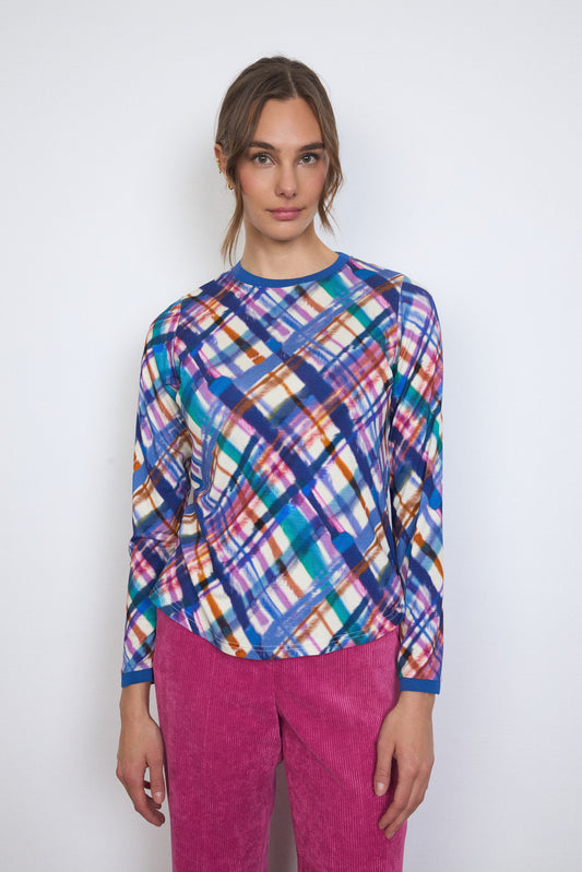 Woman wearing a colorful plaid shirt and pink pants against a white background