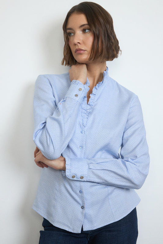 Woman wearing a light blue button-up shirt against a white background
