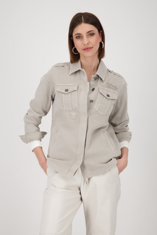 Woman wearing a light gray jacket with a brand logo on a white background